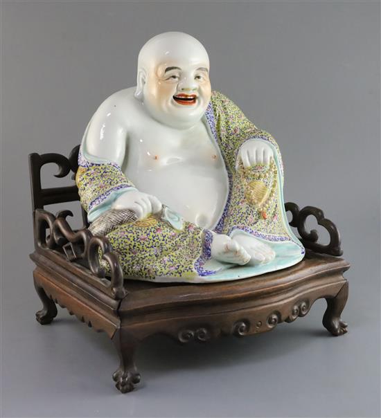 A Chinese famille rose seated figure of Budai, Republic period, H. 27cm, excluding hongmu throne stand